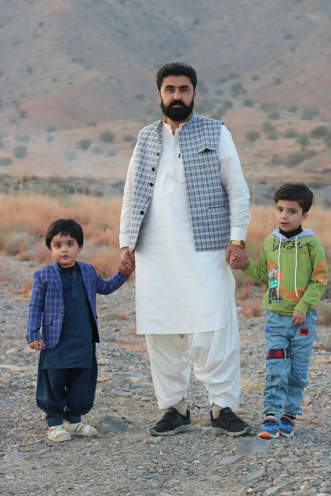 A father walking hand in hand with his two sons in Quetta