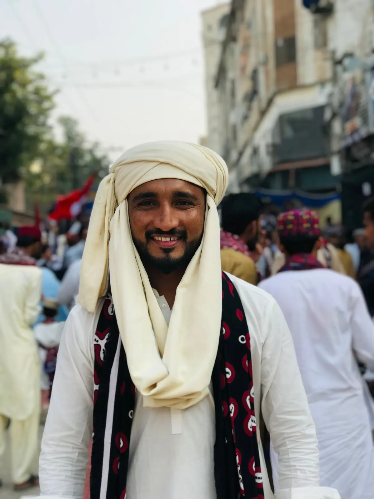 A smiling man in a white turban at an outdoor gathering
