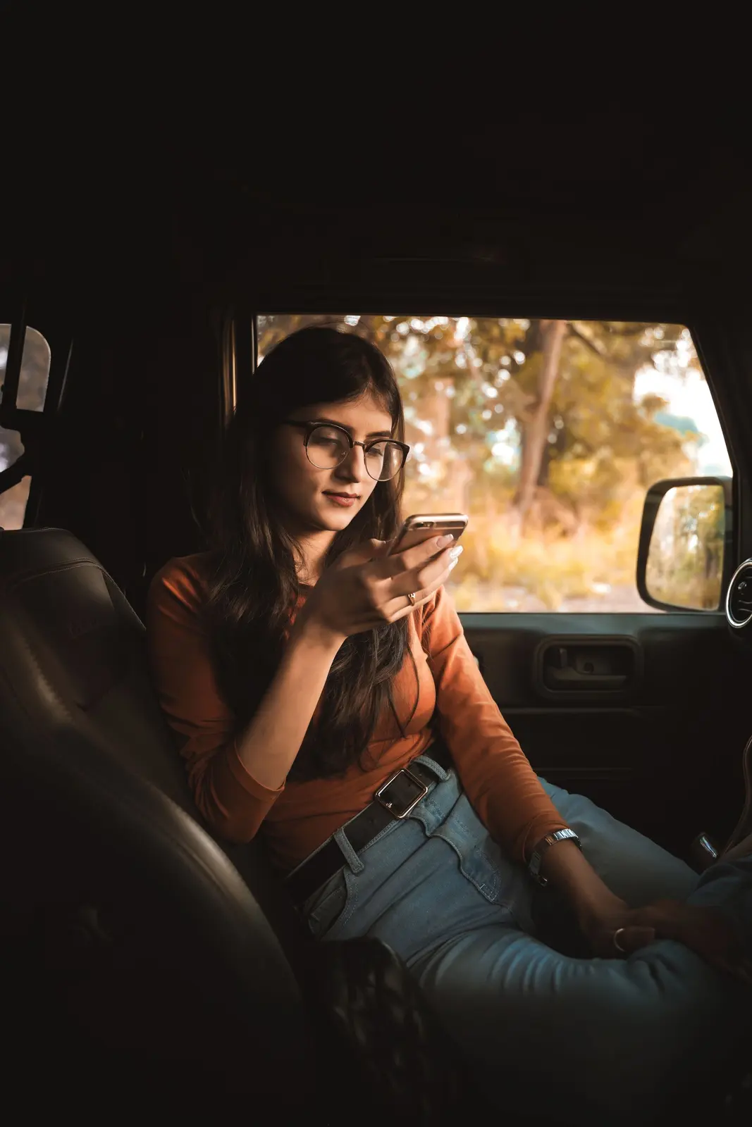 A young woman in a car looking at her phone